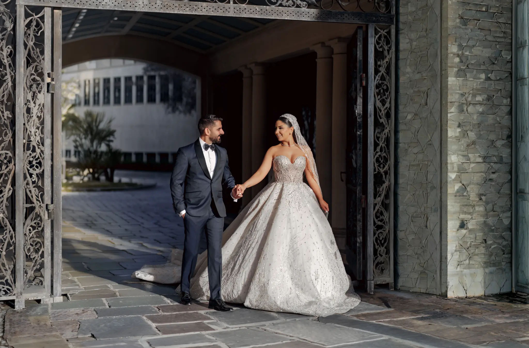 Bride and groom walking through ornate venue gates